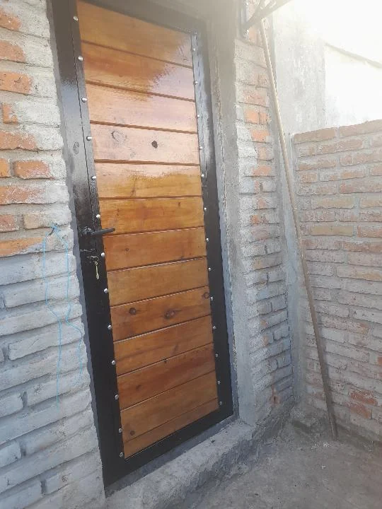 Puerta peatonal con marco negro y tablas de madera